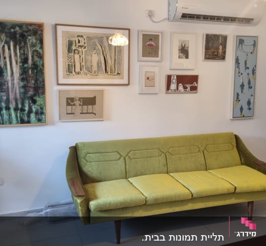 ספה ירוקה עם תמונות על הקיר ומזגן מעל